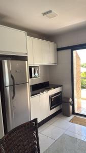 a kitchen with white cabinets and a stainless steel refrigerator at Apto lateral mar in Porto Belo