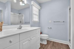 a white bathroom with a sink and a toilet at Clear For Take Off by Oak Island Accommodations in Caswell Beach