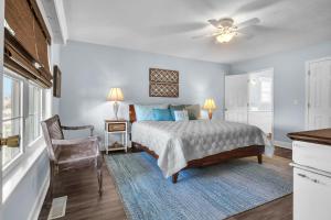 a bedroom with a bed and a chair and a window at Clear For Take Off by Oak Island Accommodations in Caswell Beach