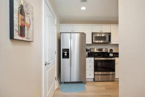 a stainless steel refrigerator in a kitchen with white cabinets at Clearly Hooked by Oak Island Accommodations in Oak Island