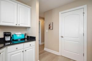 a kitchen with white cabinets and a white door at Clearly Hooked by Oak Island Accommodations in Oak Island