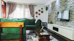 a living room with a green couch and a tv at The apartment Bwebajja 3 in Namulanda