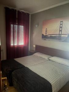 a bedroom with two beds and a bridge painting on the wall at Pensión Restaurante Verdemar in Vigo