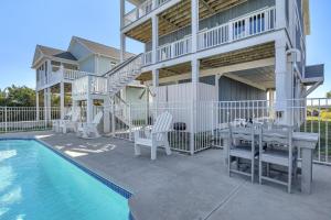 a patio with a table and chairs next to a pool at Conch Out by Oak Island Accommodations in Oak Island