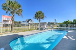 a swimming pool with palm trees and a fence at Conch Out by Oak Island Accommodations in Oak Island