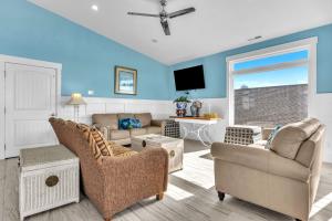 a living room with a couch and chairs and a tv at Conch Out by Oak Island Accommodations in Oak Island