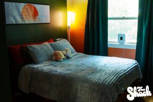 a teddy bear sitting on a bed in a bedroom at The Shack at Long Beach - A Psychedelic Getaway in Long Beach