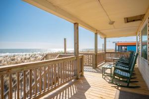 a porch with two green chairs on the beach at Dip Inn by Oak Island Accommodations in Oak Island