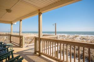 a wooden porch with chairs and the beach at Dip Inn by Oak Island Accommodations in Oak Island