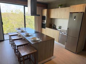 a kitchen with a island with chairs and a refrigerator at PH 3-Bedroom Private Pool in TUK in Tulum