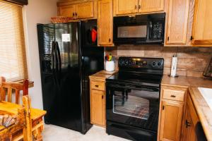 a kitchen with black appliances and wooden cabinets at Calle Condo in Green Valley