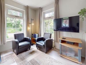 ein Wohnzimmer mit zwei Sesseln und einem Flachbildfernseher in der Unterkunft Borre Bos in Diever