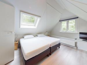 ein weißes Schlafzimmer mit einem Bett und zwei Fenstern in der Unterkunft Borre Bos in Diever