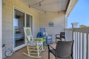a porch with chairs and a table and a window at Dolphy Daze by Oak Island Accommodations in Oak Island