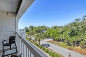 a balcony with a view of a street and trees at Dolphy Daze by Oak Island Accommodations in Oak Island