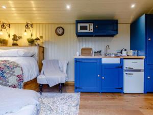 a kitchen with blue cabinets and a bed and a microwave at 1 Bed in Lydney oc-85862 in Bream