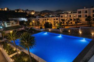 a large blue swimming pool at night with buildings at Panoramic View, Cozy apartment M'diq in M'diq