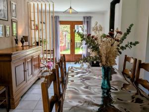 a dining room with a table with a vase of flowers at Gîte paisible dans ancienne ferme comtoise avec animaux acceptés - FR-1-583-416 in Saint-Bresson
