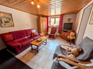 a living room with a red couch and a tv at Gîte paisible dans ancienne ferme comtoise avec animaux acceptés - FR-1-583-416 in Saint-Bresson