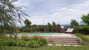 a swimming pool with a bench next to a garden at Quita penas in Los Reartes