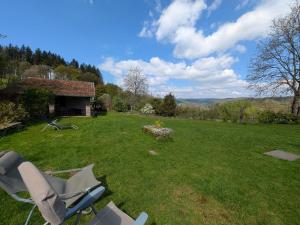 a yard with a chair in the grass at Gîte paisible dans ancienne ferme comtoise avec animaux acceptés - FR-1-583-416 in Saint-Bresson