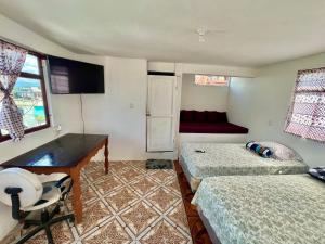 ein Zimmer mit zwei Betten und einem Schreibtisch in der Unterkunft Hotel Henderson in San Pedro La Laguna
