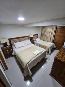 a hotel room with two beds and two lamps at Hostal Aires del Sur Renovado in Rancagua
