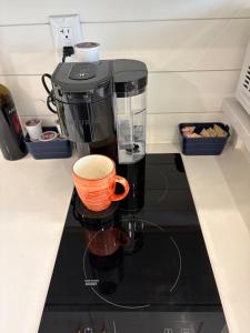 a coffee maker sitting on a counter with an orange cup at Oceanfront Tiny Retreat in Holden Beach