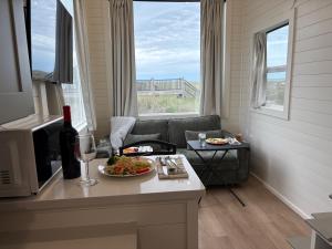 a living room with a table with a plate of food at Oceanfront Tiny Retreat in Holden Beach