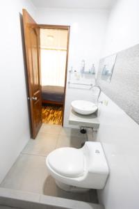 a bathroom with a white toilet and a sink at Casa completa, 5 dormitorios y jardín in Ayacucho +12 photos