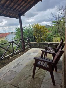 two wooden benches sitting on a patio with a view at Chalés serra negra in Bezerros