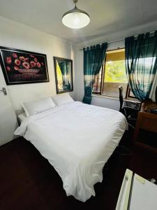 a bedroom with a large white bed and a window at Premium Executive Room in Sandton