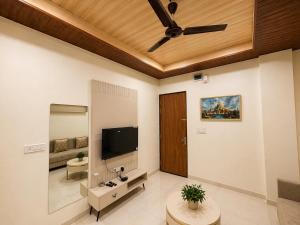 a living room with a ceiling fan and a television at Hotel Aventus Suites Indore in Indore