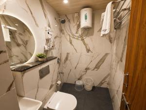 a white bathroom with a toilet and a sink at Hotel Aventus Suites Indore in Indore +25 photos