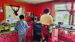 two children standing in a kitchen with red walls at Phantom rock view homestay in Namara
