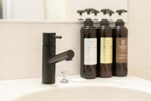 a bathroom sink with three bottles of soap at Saitama Grand Hotel Honjo in Honjo