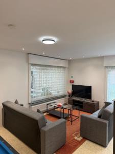 a living room with two couches and a flat screen tv at The Wandering House in Tremelo