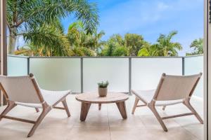 two chairs and a table on a balcony with palm trees at Pet Friendly Modern Oasis with Private Pool in Noosaville