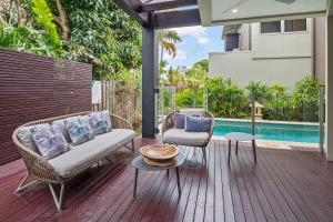 a patio with a couch and chairs next to a pool at Modern airy duplex steps to River heated pool in Noosaville