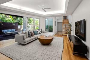a living room with a couch and a coffee table at Modern airy duplex steps to River heated pool in Noosaville
