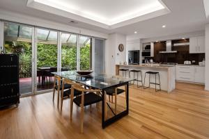 a kitchen and dining room with a glass table and chairs at Modern airy duplex steps to River heated pool in Noosaville