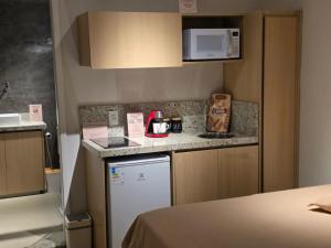 a small kitchen with a refrigerator and a microwave at Chalé loft reserva Refúgio nas Montanhas in Marechal Floriano