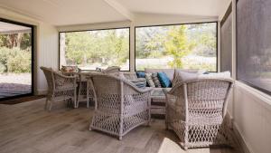 a screened in porch with wicker chairs and a table at Kingfisher Cottage in Broughton Vale