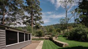 a backyard with a building and a grass yard at Kingfisher Cottage in Broughton Vale