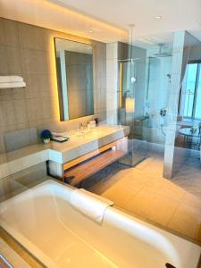 a bathroom with a tub and a sink and a mirror at À La Carte Hạ Long in Ha Long