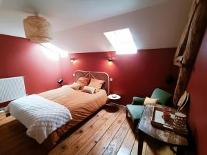 a bedroom with red walls and a bed and a table at Chambre d'hôtes Le Colibri in Épinal