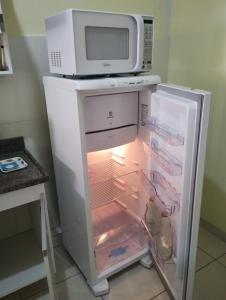 a microwave sitting on top of an open refrigerator at Ap completo 01 quarto com ar condicionado, wi-fi in Viçosa