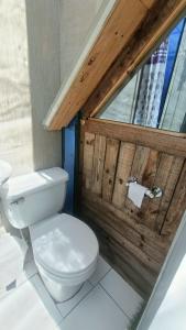 a bathroom with a toilet and a wooden wall at Cabaña Bambú - Roca Glamping Suesca in Santa Isabel