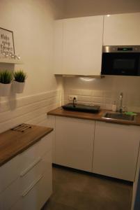 ヴロツワフにあるMagnolia Centrum Studioの白いキャビネットとシンク付きのキッチン