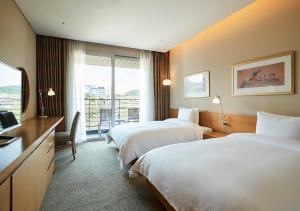ein Hotelzimmer mit zwei Betten und einem Fernseher in der Unterkunft Rolling Hills Hotel in Hwaseong + 20 Fotos